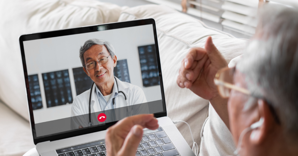 Man sitting on a couch watching a doctor on his laptop