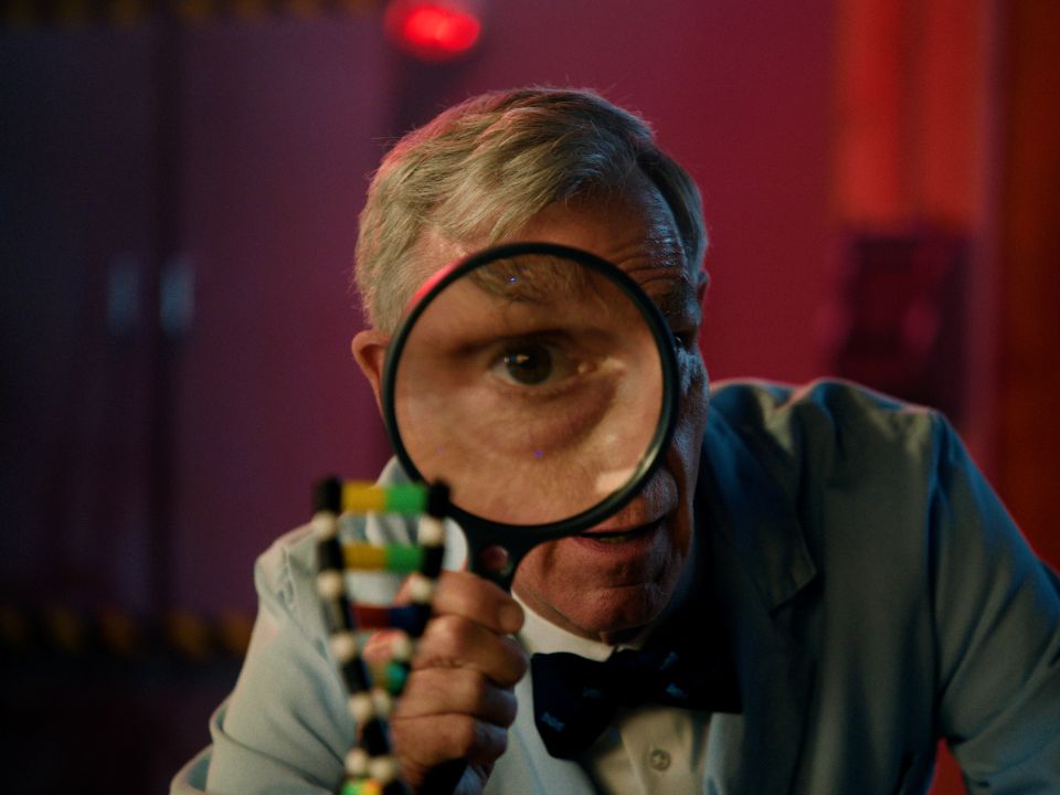 Bill Nye looking through magnifying glass